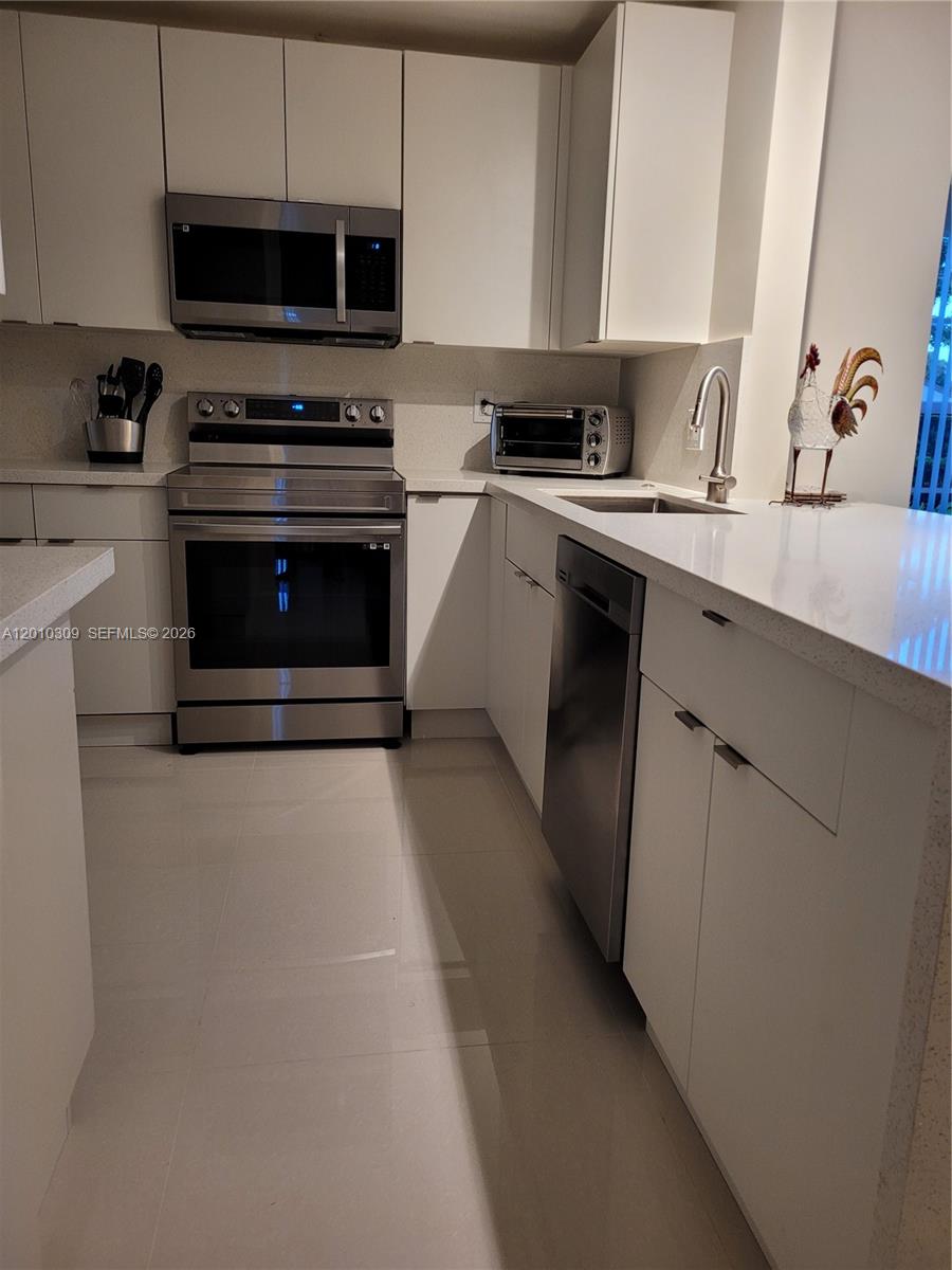 A modern kitchen features white cabinets, stainless steel appliances, and light-colored countertops — 8101 SW 24th Ct # 108, Davie FL 33324, DAVIE, FL