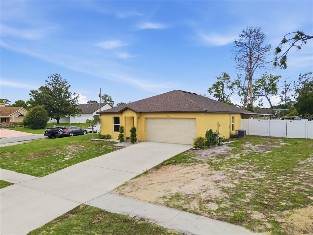 A yellow single-story house with a two-car garage and a concrete driveway — 10198 ELGIN BOULEVARD, SPRING HILL, FL