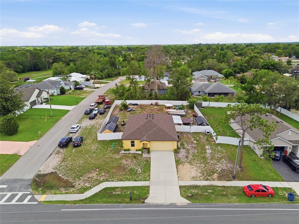 An aerial view shows a yellow house with a brown roof and a large fenced yard — 10198 ELGIN BOULEVARD, SPRING HILL, FL