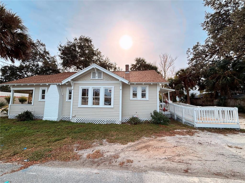 A single-story house with light siding, a white chimney, and a wooden wheelchair ramp — 616 N DIXIE FREEWAY, NEW SMYRNA BEACH, FL