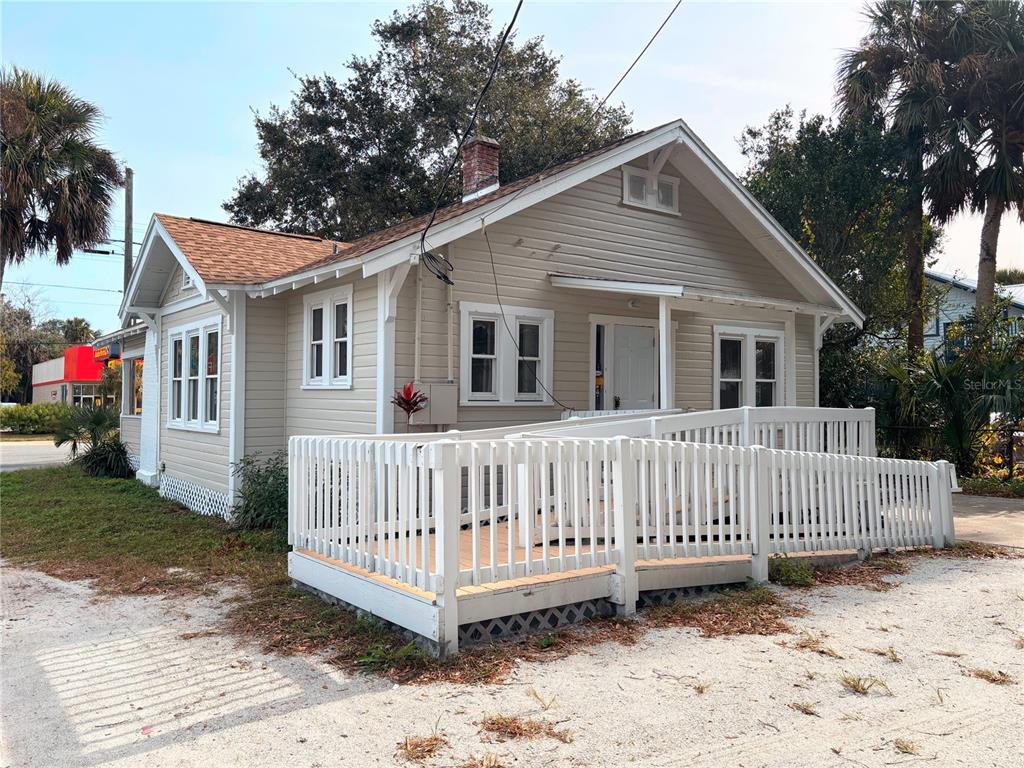 A single-story house with beige siding and a white wooden wheelchair ramp in front — 616 N DIXIE FREEWAY, NEW SMYRNA BEACH, FL