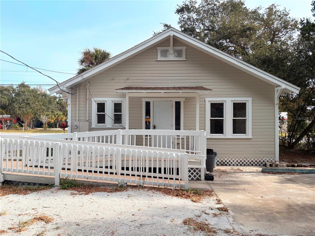 A single-story house with beige siding, a white front door, and a wooden wheelchair ramp — 616 N DIXIE FREEWAY, NEW SMYRNA BEACH, FL