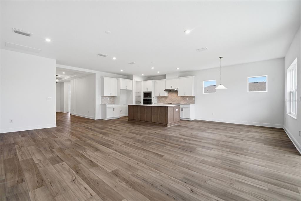 A spacious open-concept kitchen features white cabinetry, a wood-toned island, and light wood-look flooring — 11830 RICHMOND TRAIL, PARRISH, FL