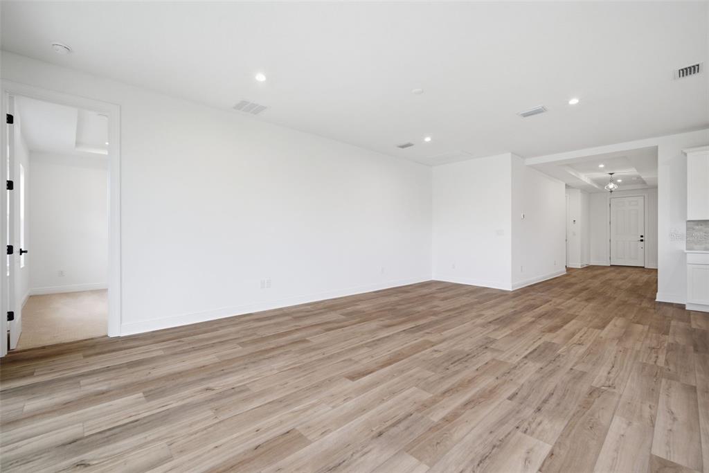 An empty room with light wood-look flooring, white walls, and a doorway leading to another space — 11830 RICHMOND TRAIL, PARRISH, FL