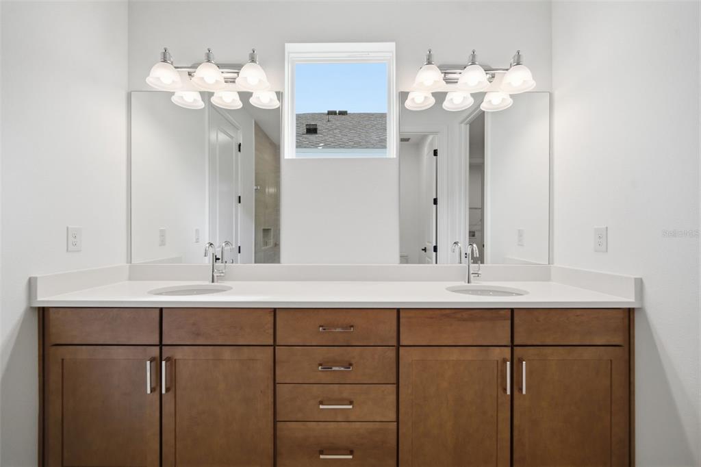 A bathroom vanity with two sinks, wooden cabinets, and a central window between two mirrors — 11830 RICHMOND TRAIL, PARRISH, FL