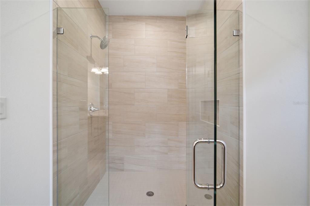 A walk-in shower features light-toned horizontal wall tiles, a glass door, and a built-in niche — 11830 RICHMOND TRAIL, PARRISH, FL