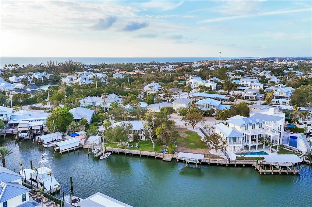 An aerial view shows waterfront homes with private docks along a canal near the ocean — 140 DAMFINO STREET, BOCA GRANDE, FL