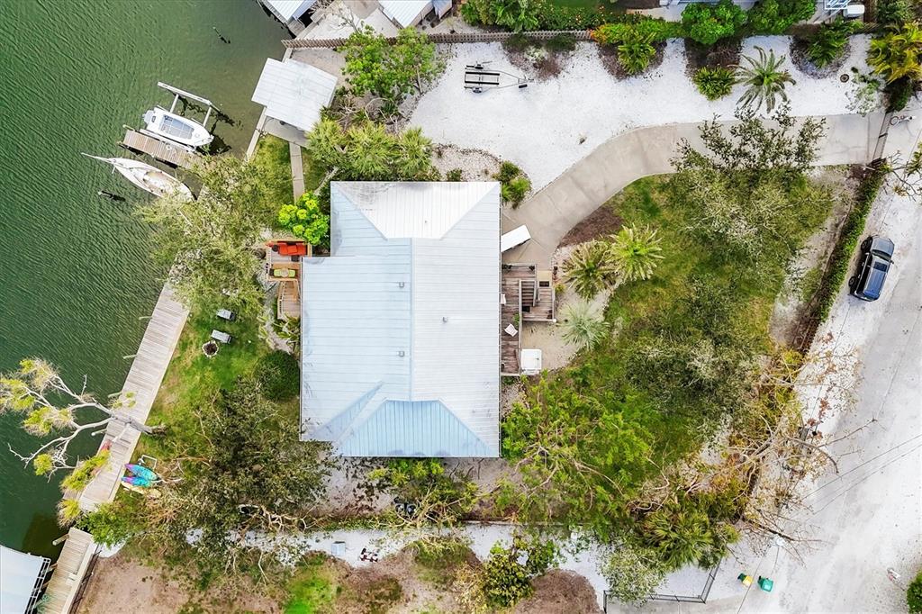 An aerial view shows a house with a metal roof, a dock, and a driveway — 140 DAMFINO STREET, BOCA GRANDE, FL