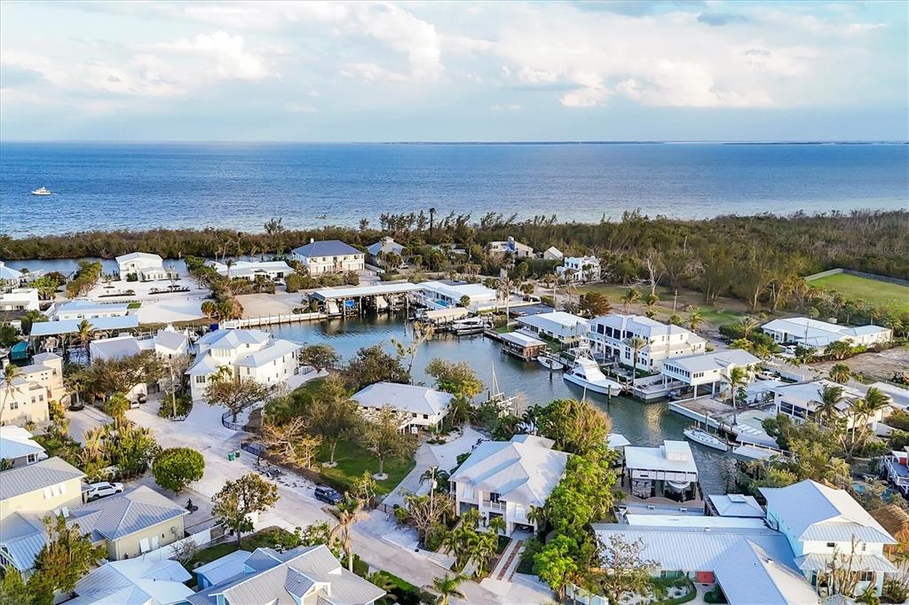 An aerial view shows waterfront homes with private boat docks along a canal near the ocean — 140 DAMFINO STREET, BOCA GRANDE, FL