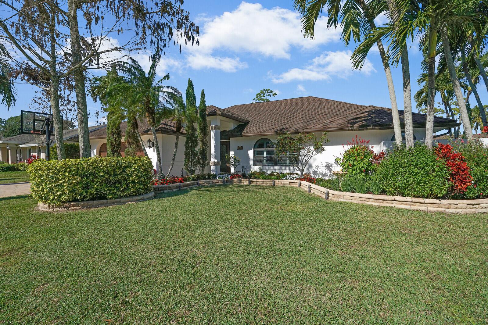 A single-story house with a white exterior, brown roof, and a landscaped front yard — 1313 Brampton Cove, Wellington FL 33414, WELLINGTON, FL
