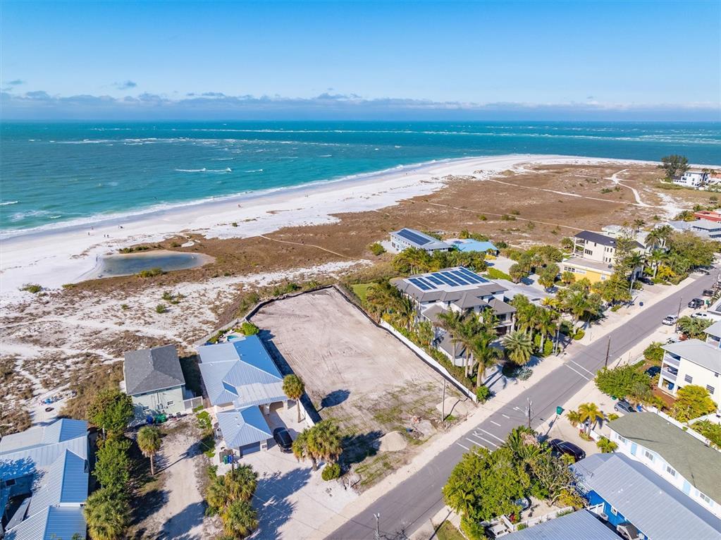 An aerial view shows a vacant coastal lot situated between residential homes and the beach — 769 N SHORE DRIVE, ANNA MARIA, FL