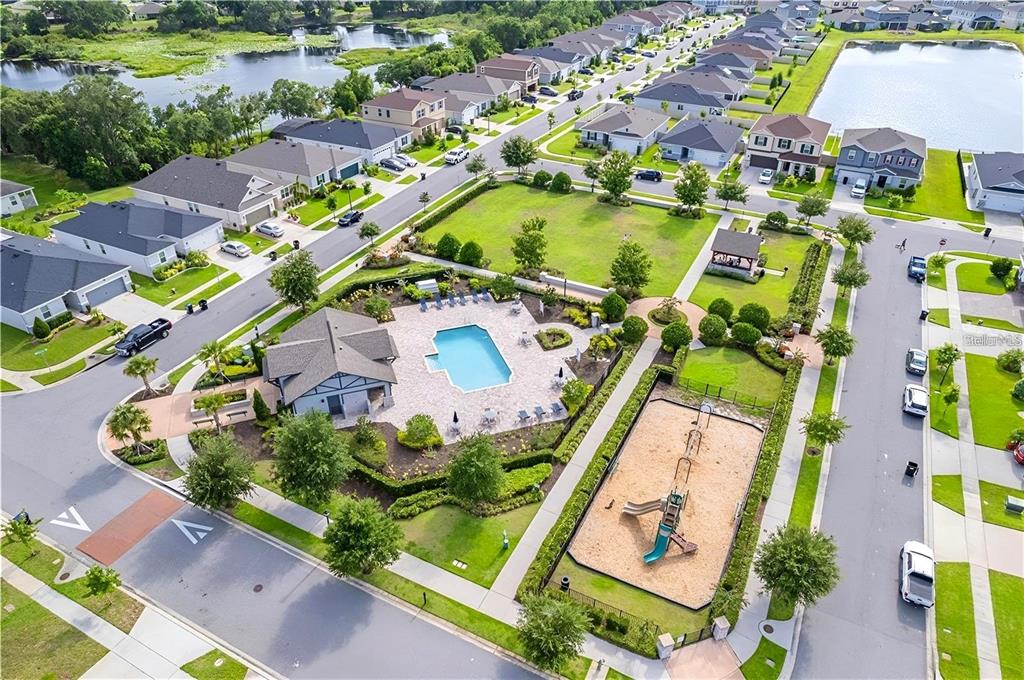 An aerial view shows a community pool, playground, and surrounding suburban houses near a lake — 13941 RUSHING CREEK RUN, ORLANDO, FL