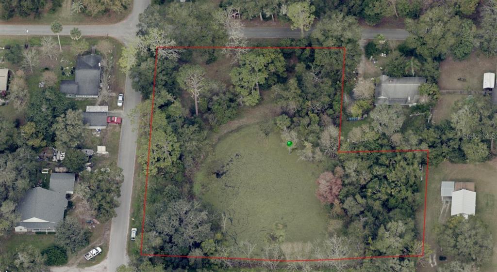 An aerial view shows a wooded lot containing a large pond outlined in red — WESTLAKE DRIVE, LAKE HELEN, FL