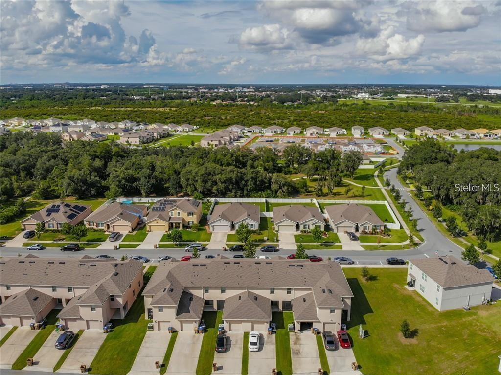 An aerial view shows a suburban neighborhood with townhomes, single-family houses, and surrounding green space — 1842 KATZ CROSSING DRIVE, KISSIMMEE, FL
