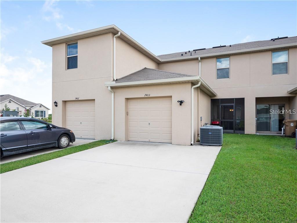 A two-story townhouse exterior features two garages, a concrete driveway, and a screened-in patio — 1842 KATZ CROSSING DRIVE, KISSIMMEE, FL