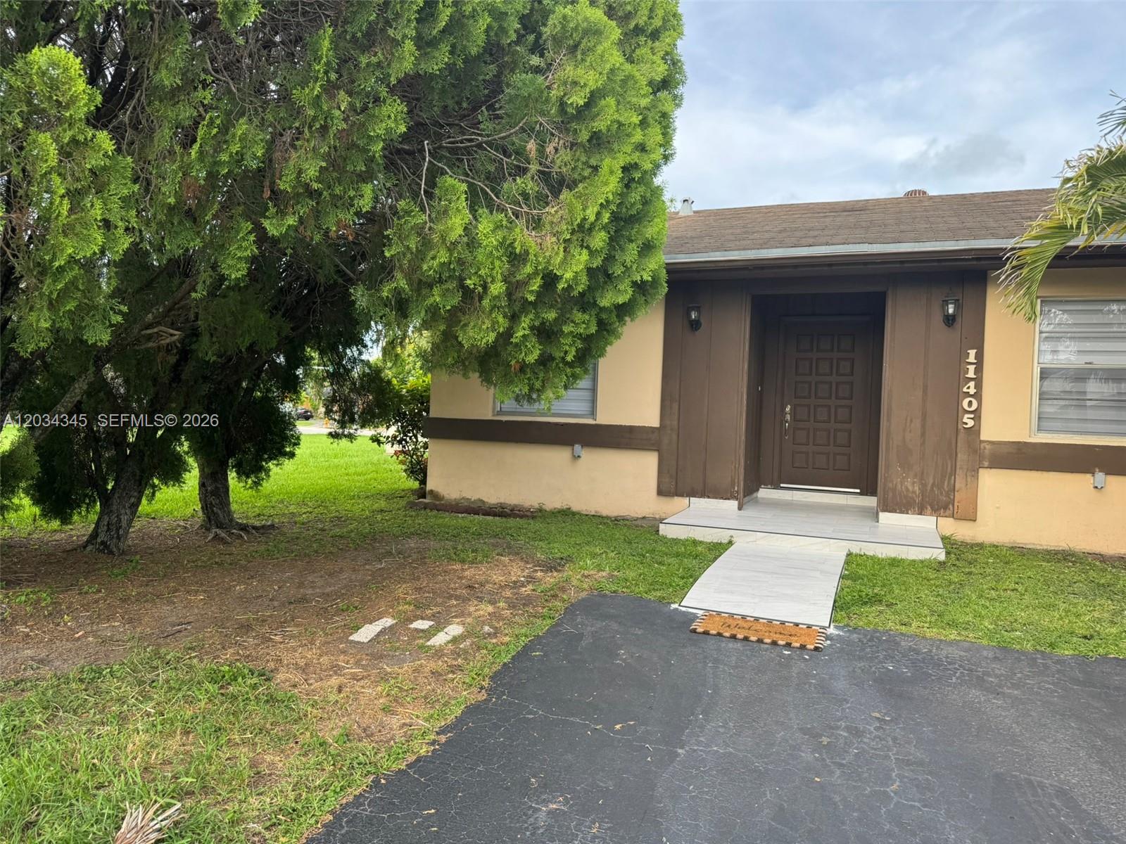 A tan house with brown trim features a front door and a paved walkway — 11405 SW 122nd Ct, Miami FL 33186, MIAMI, FL
