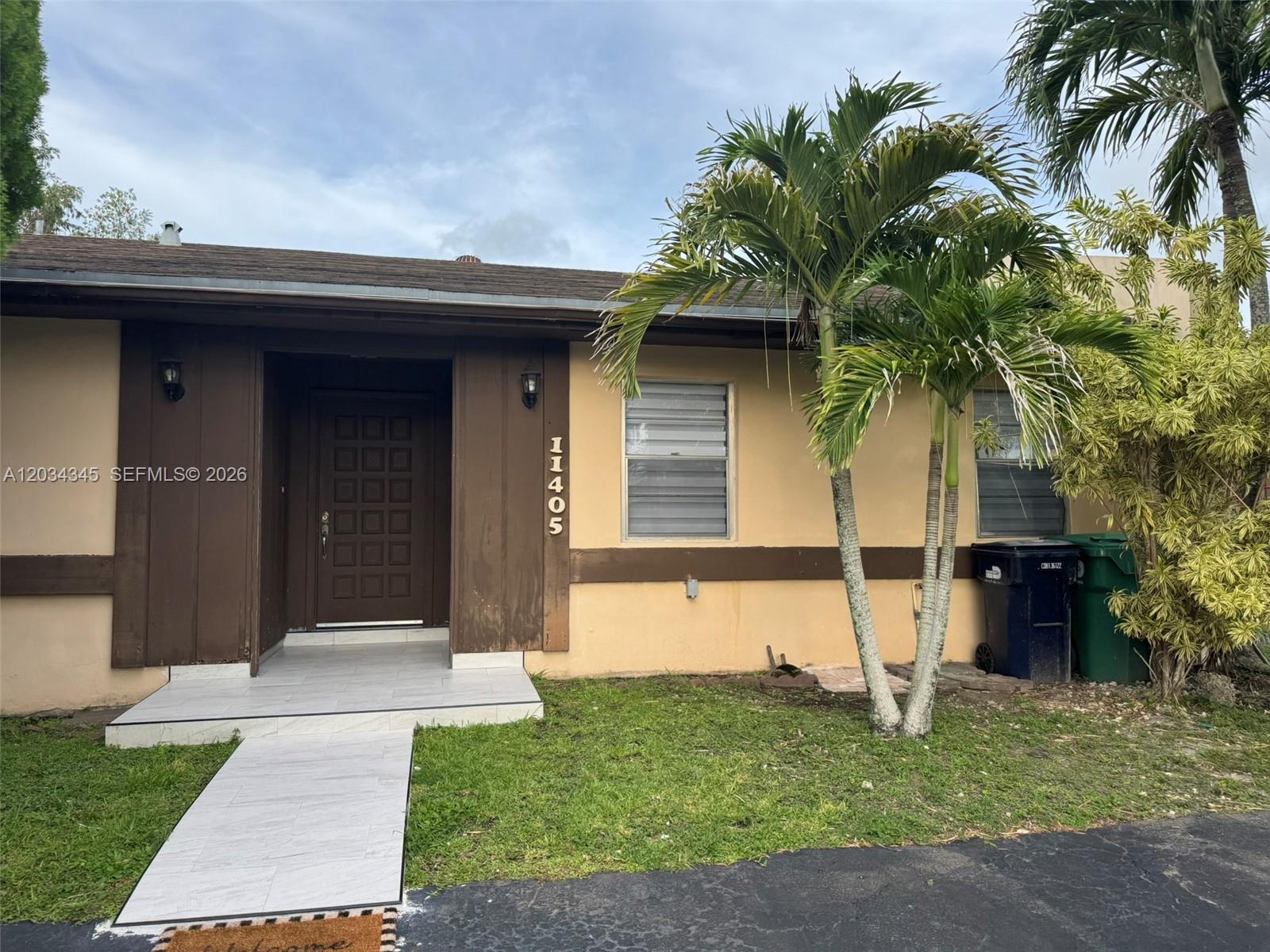 A single-story house exterior features a brown front door, tiled walkway, and palm trees — 11405 SW 122nd Ct, Miami FL 33186, MIAMI, FL