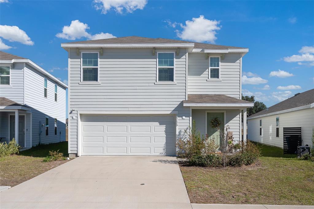 A two-story house with light gray siding, a two-car garage, and a front entrance — 1265 NW 248TH DRIVE, NEWBERRY, FL