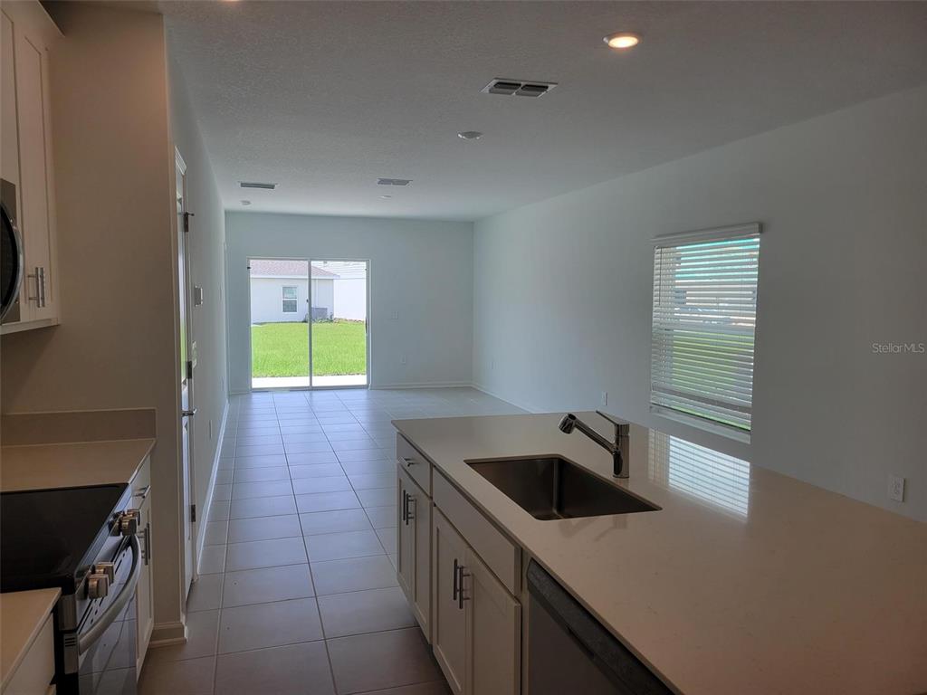 A kitchen with white cabinets and a quartz island overlooks an open living area — 5635 VINYASA ROAD, CLERMONT, FL