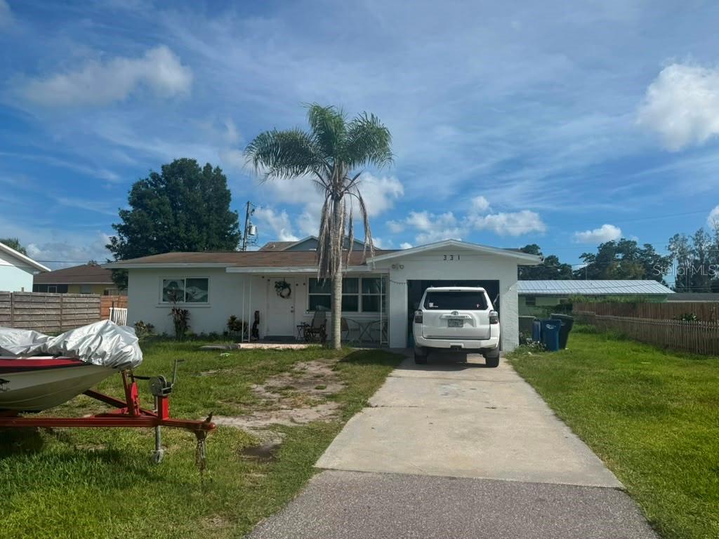 A single-story house with a white exterior, a concrete driveway, and a palm tree out front — 331 51ST STREET COURT W, PALMETTO, FL