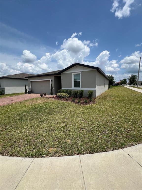 A single-story house with a tan exterior, a two-car garage, and a front lawn — 364 GUADLUPE STREET, HAINES CITY, FL