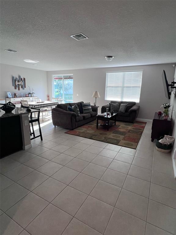 An open-concept living and dining area features tile flooring, neutral walls, and a sliding door — 364 GUADLUPE STREET, HAINES CITY, FL