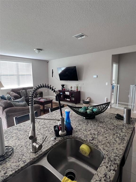 A kitchen island with a stainless steel sink overlooks a living room with a television — 364 GUADLUPE STREET, HAINES CITY, FL