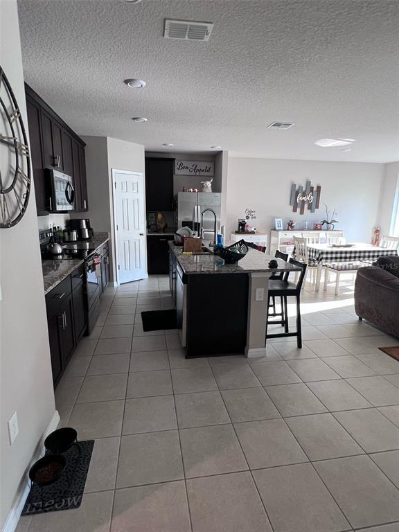 A kitchen with dark cabinets, granite countertops, and a central island opens to a dining area — 364 GUADLUPE STREET, HAINES CITY, FL