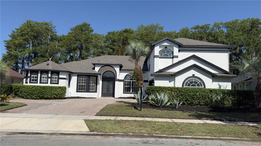 A two-story house with white stucco walls, dark trim, and a paved driveway — 118 FAIRWAY POINTE CIRCLE, ORLANDO, FL