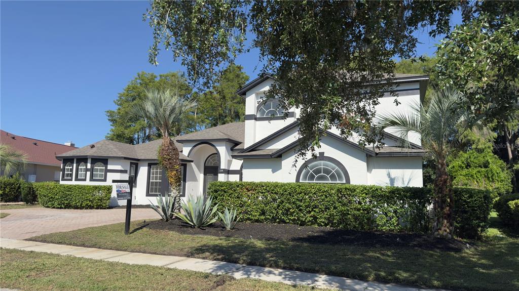 A two-story house with white stucco walls, dark trim, and a landscaped front yard — 118 FAIRWAY POINTE CIRCLE, ORLANDO, FL