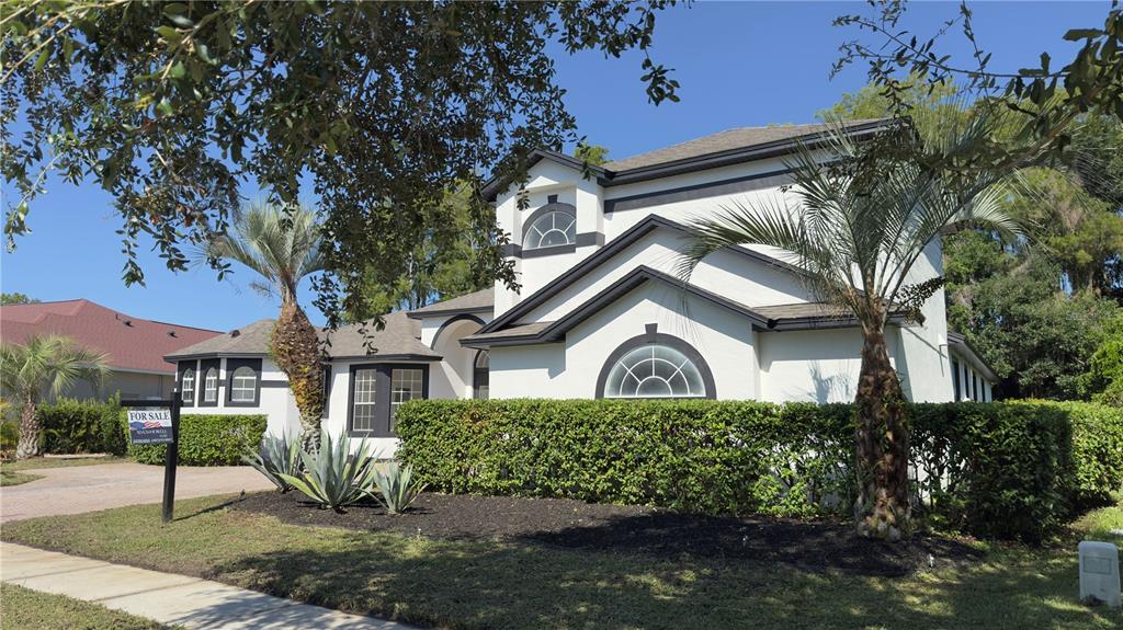 A two-story white house with dark trim, a hedge, and palm trees in the front yard — 118 FAIRWAY POINTE CIRCLE, ORLANDO, FL