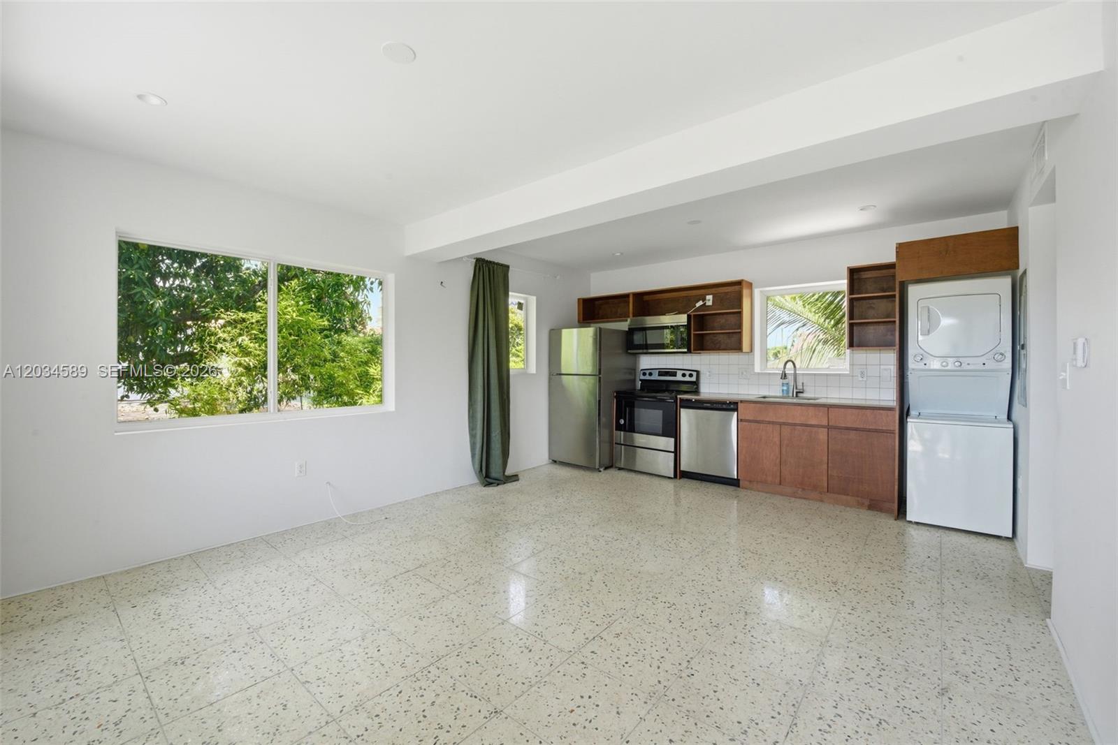 A kitchen and living area with white walls, terrazzo floors, and stainless steel appliances — 127 NW 74th St # 3, Miami FL 33150, MIAMI, FL
