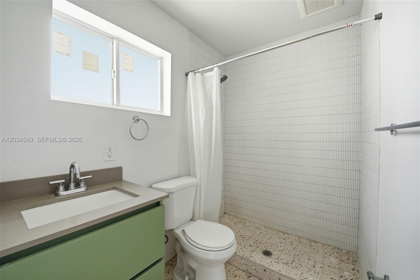 A bathroom features a green vanity, a white toilet, and a tiled walk-in shower — 127 NW 74th St # 3, Miami FL 33150, MIAMI, FL