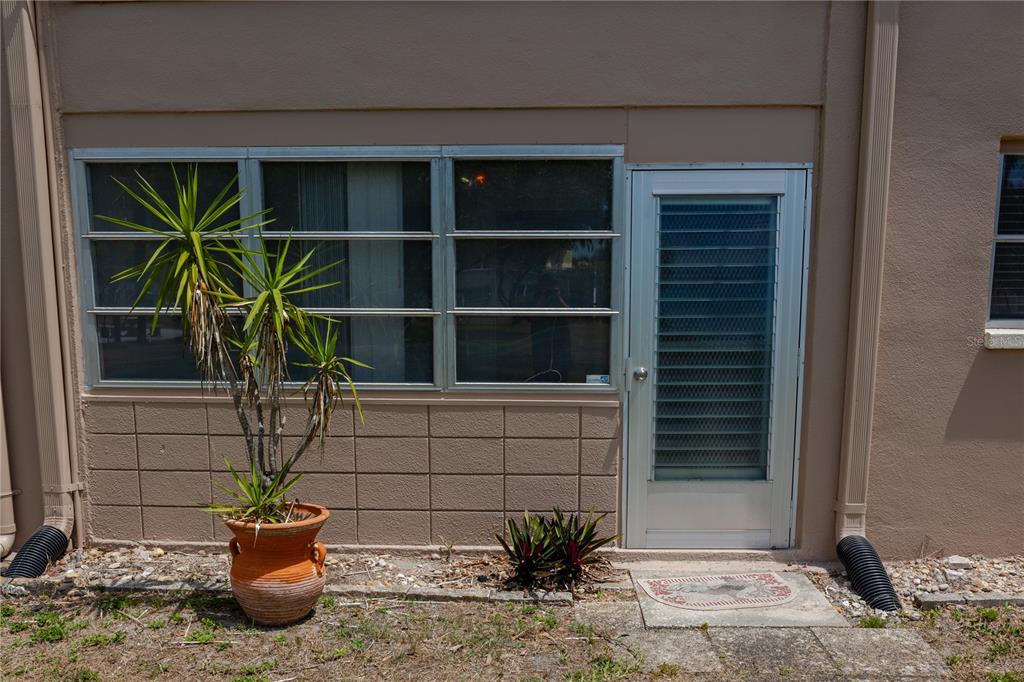 An exterior view of a tan building with a window, a door, and potted plants — 6645 1ST AVENUE N UNIT 103, ST PETERSBURG, FL