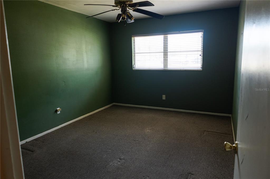 An empty bedroom features dark green walls, gray carpeting, and a ceiling fan — 6645 1ST AVENUE N UNIT 103, ST PETERSBURG, FL