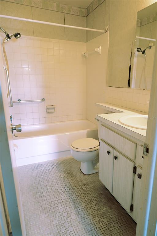 A bathroom features a white tub-shower combination, a toilet, and a vanity with a mirror — 6645 1ST AVENUE N UNIT 103, ST PETERSBURG, FL