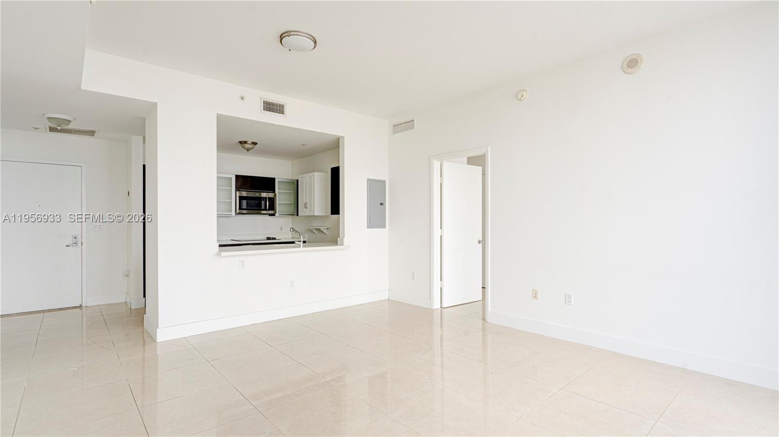 An empty living area with tile flooring features an open kitchen pass-through window — 90 SW 3rd St # 10, Miami FL 33130, MIAMI, FL