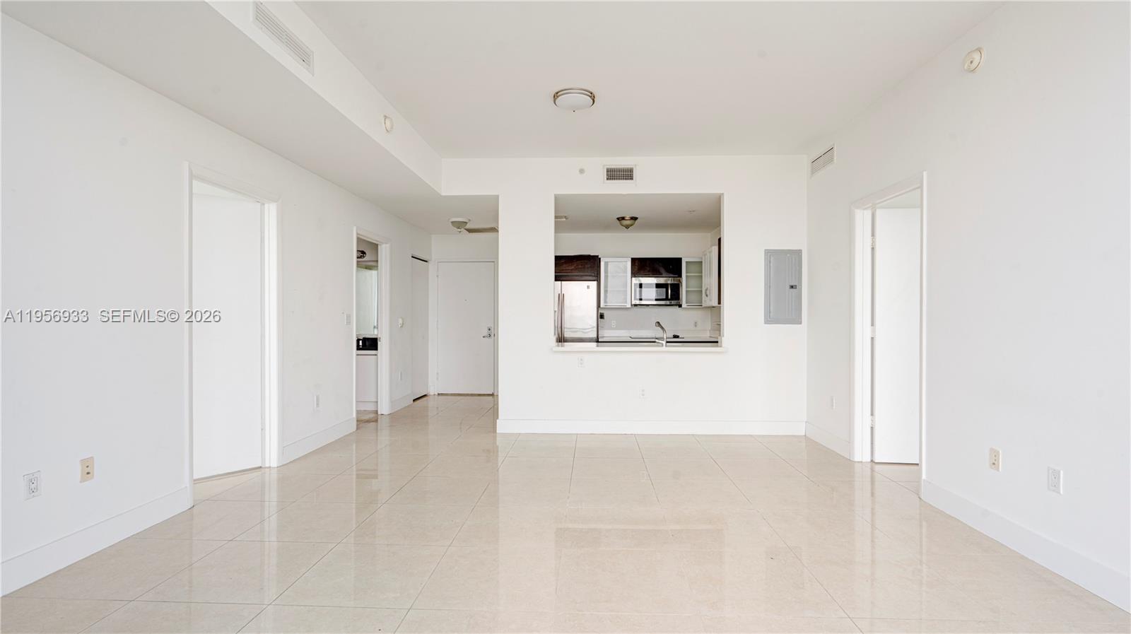 An open living area features white walls, light tile flooring, and a kitchen pass-through window — 90 SW 3rd St # 10, Miami FL 33130, MIAMI, FL