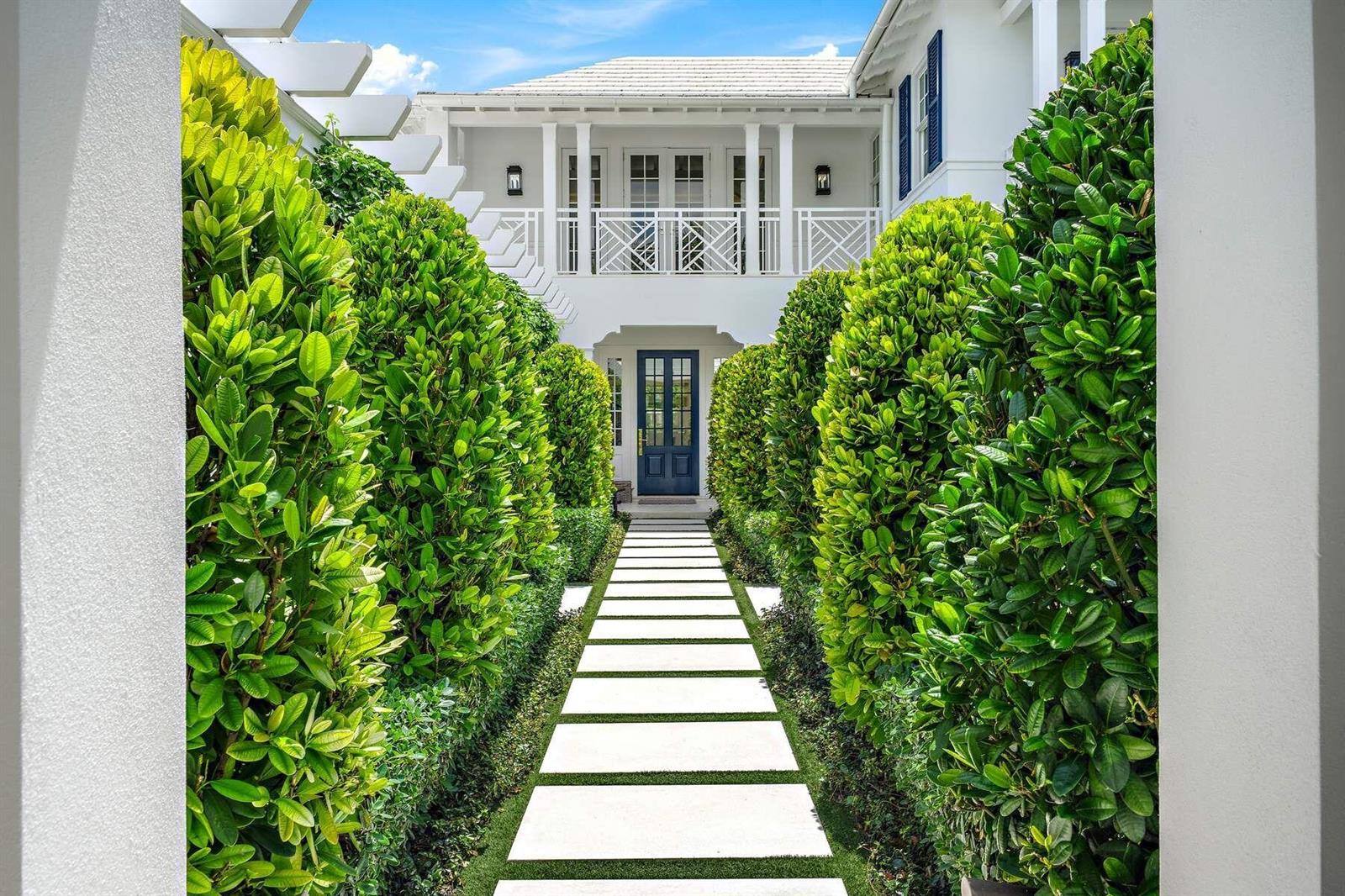 A stone walkway leads through manicured hedges to the entrance of a white two-story house — 608 Island Drive, Palm Beach FL 33480, PALM BEACH, FL
