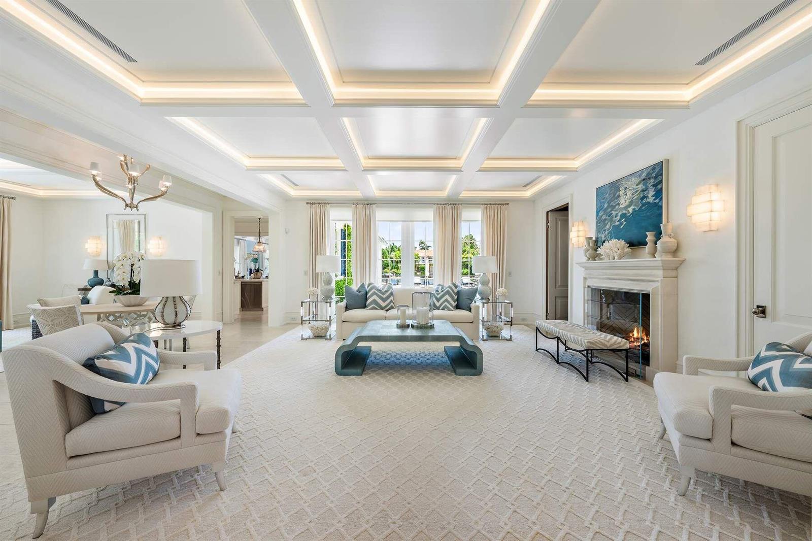 A bright living room features a coffered ceiling, fireplace, and neutral furniture with blue accents — 608 Island Drive, Palm Beach FL 33480, PALM BEACH, FL