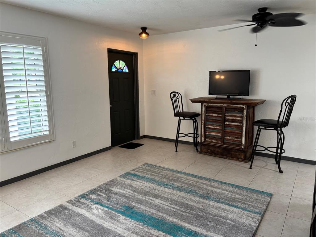 A room with tile flooring, a rug, a black door, and a high-top table with chairs — 2020 WORLD PARKWAY BOULEVARD UNIT 10, CLEARWATER, FL