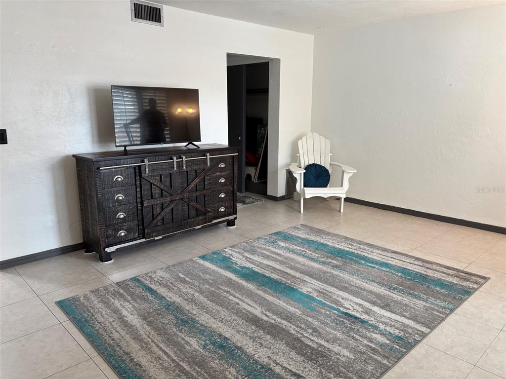 A living room features a dark wood media console, a white chair, and a patterned rug — 2020 WORLD PARKWAY BOULEVARD UNIT 10, CLEARWATER, FL