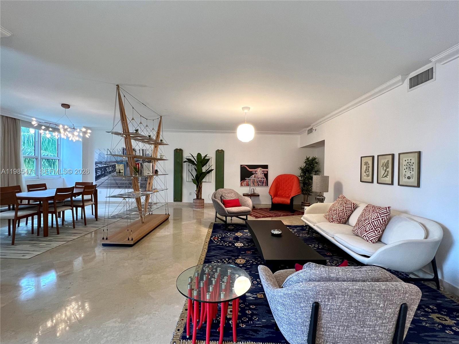 A spacious living and dining room features polished floors, modern furniture, and a unique shelving unit — 445 Grand Bay Dr # 310, Key Biscayne FL 33149, KEY BISCAYNE, FL
