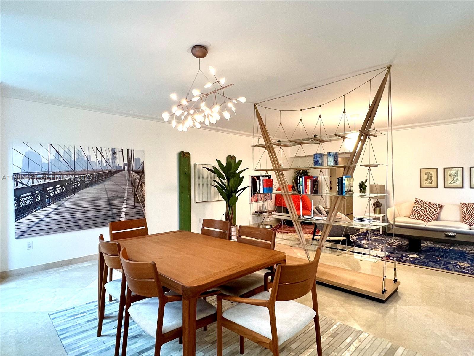 A dining area with a wooden table and chairs sits beside a unique suspended shelving unit — 445 Grand Bay Dr # 310, Key Biscayne FL 33149, KEY BISCAYNE, FL