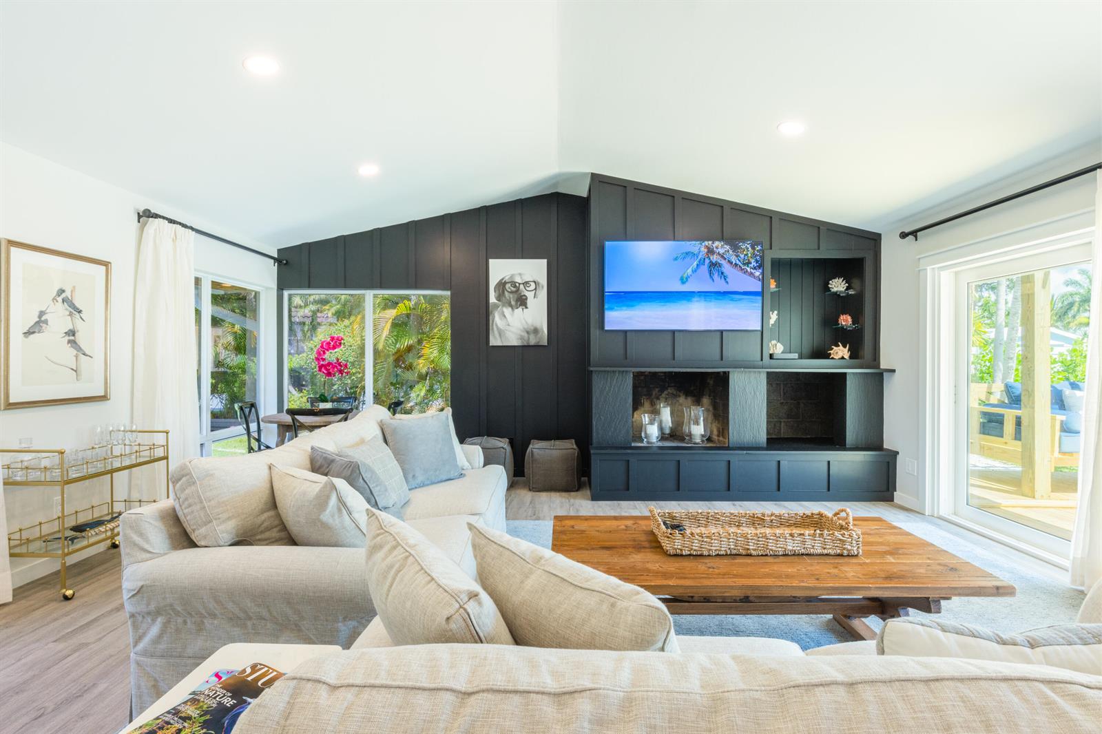 A living room features a vaulted ceiling, a black fireplace wall, and a light-colored sofa — 1967 NW Palmetto Terrace, Stuart FL 34994, STUART, FL