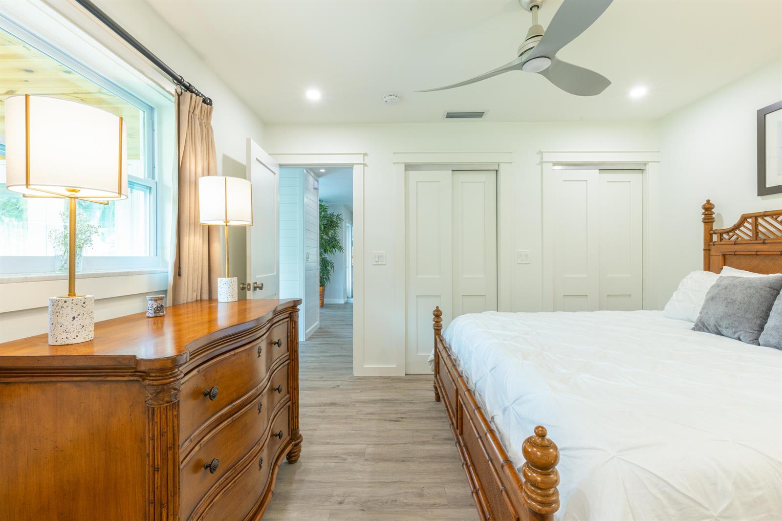 A bedroom features a wooden bed frame, a matching dresser, and two white closet doors — 1967 NW Palmetto Terrace, Stuart FL 34994, STUART, FL