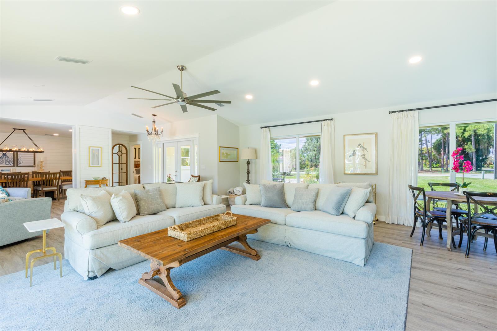 A bright living room features two beige sofas, a wooden coffee table, and dining area — 1967 NW Palmetto Terrace, Stuart FL 34994, STUART, FL