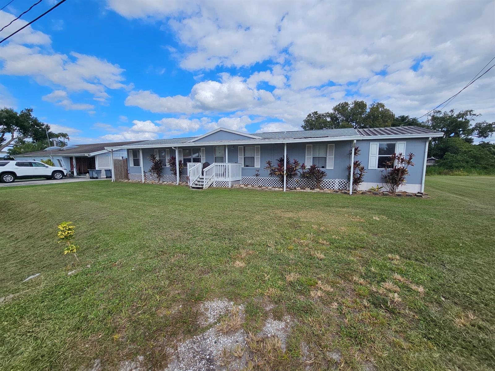 A single-story light blue house with a white front porch and lattice skirting — 3222 SE 34th Avenue, Okeechobee FL 34974, OKEECHOBEE, FL