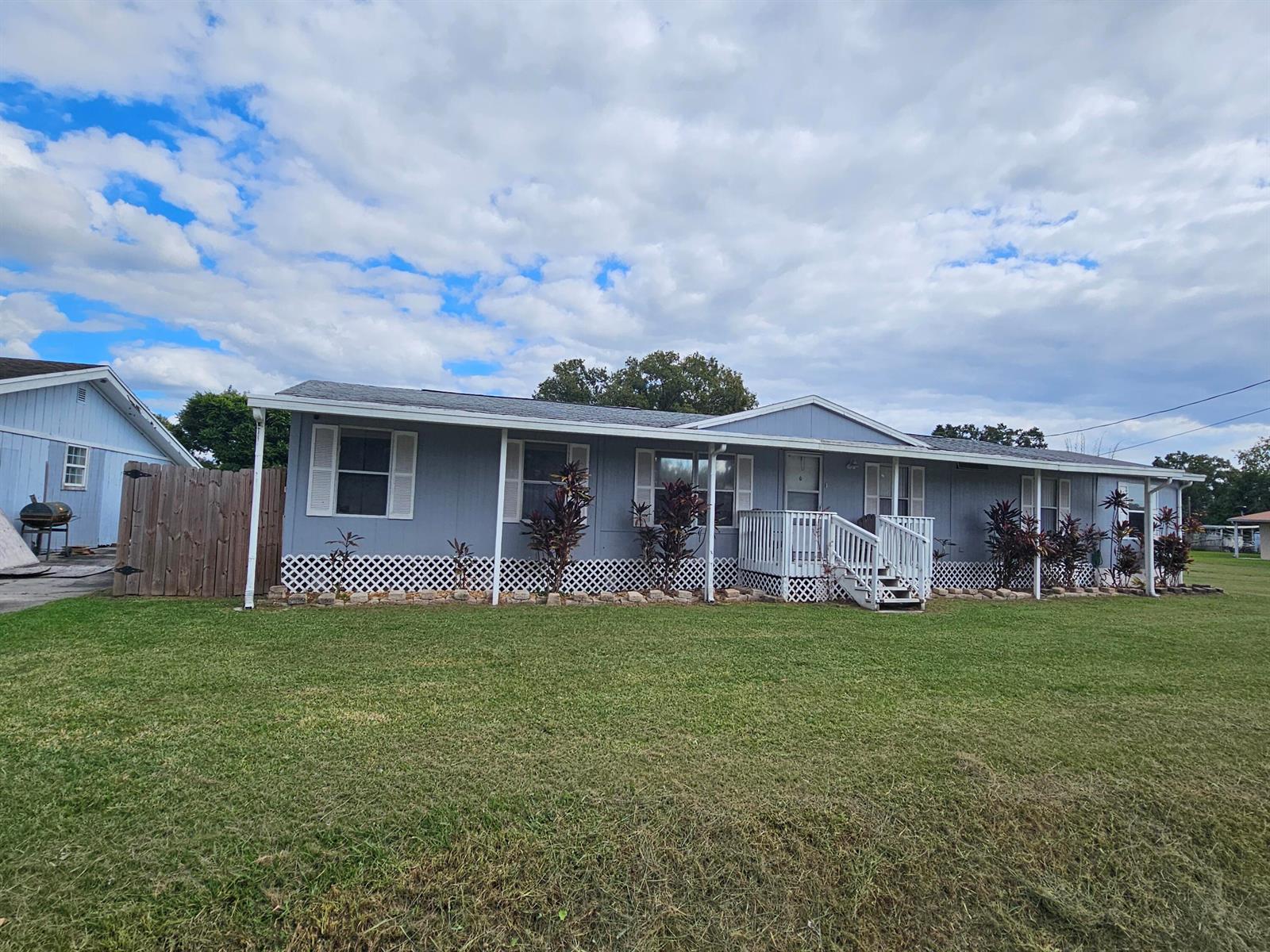 A light blue manufactured home with a white porch and lattice skirting under a cloudy sky — 3222 SE 34th Avenue, Okeechobee FL 34974, OKEECHOBEE, FL