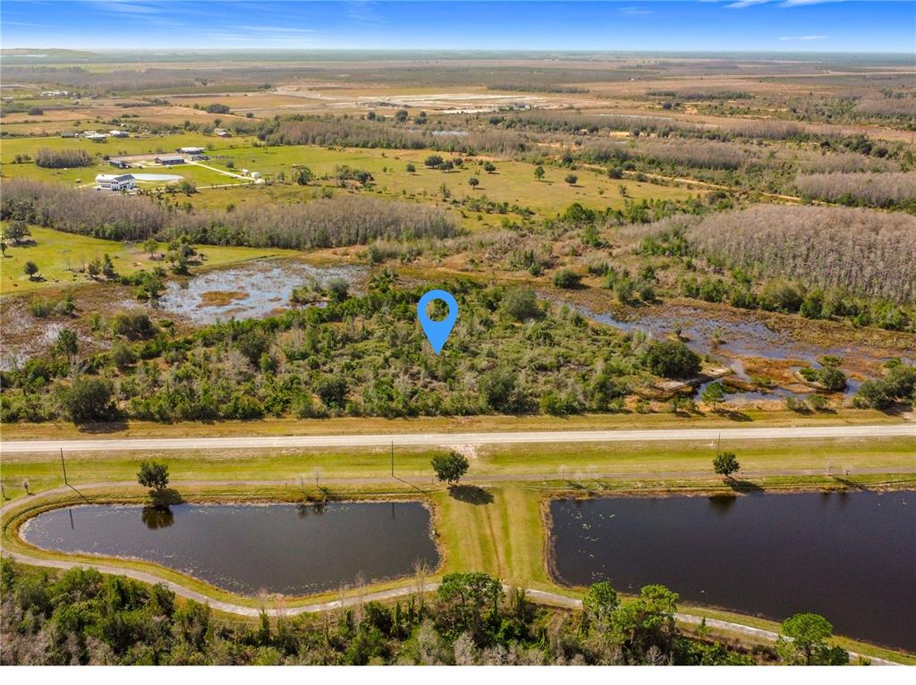 An aerial view shows a wooded lot with a blue location pin near a road — 0 COMMUNITY CENTER ROAD, ST CLOUD, FL
